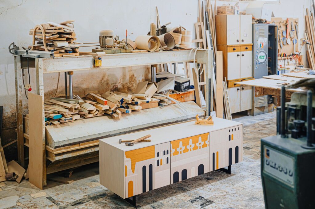 Un mobile basso dal design moderno con decorazioni geometriche ispirate ad architetture classiche, posizionato in un laboratorio di falegnameria.